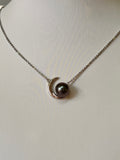 Rhodium-plated silver necklace featuring a unique moon-inspired design, set with a Tahitian pearl. Elegant and timeless.